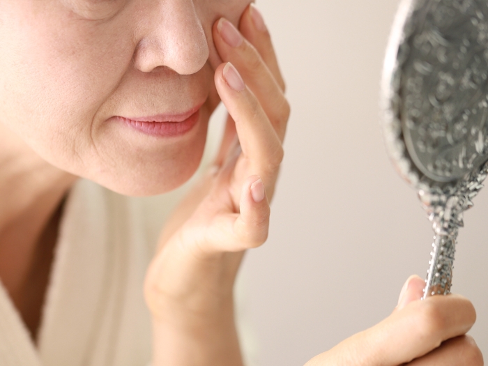 Older woman checks her face in the mirror