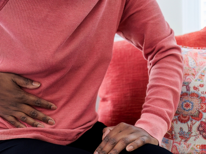 man in pink shirt close up with hand on stomach